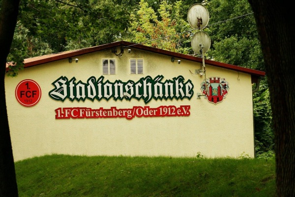 Die Stadionschänke mit Vereinswappen unter Bäumen